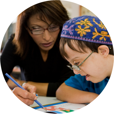 A Young Jewish boy with special needs and his teaching doing a worksheet