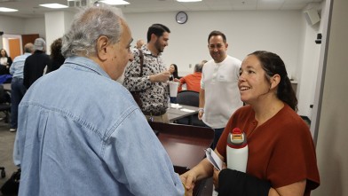 A man and woman shake hands during a meeting in a conference room.