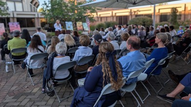 People sit in rows listening to someone at a podium speak about victims of the October 7 attacks on Israel.