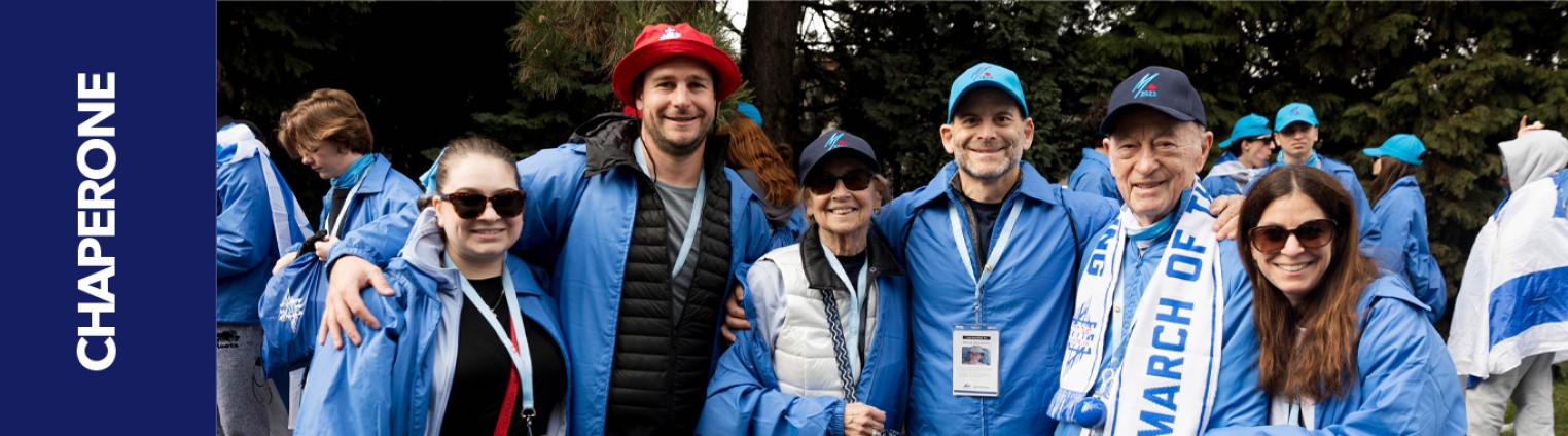A group of six people wearing blue jackets and hats, standing together outdoors, with a banner on the left reading "CHAPERONE."