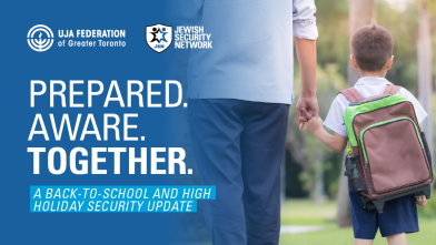 A man holding hands with a young boy, who is wearing a backpack, walking together outdoors. Text on the image reads: "Prepared. Aware. Together. A back-to-school and high holiday security update."
