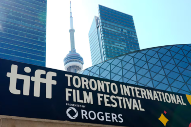 A sign for the "Toronto International Film Festival" with the CN Tower visible in the background, under a clear blue sky.