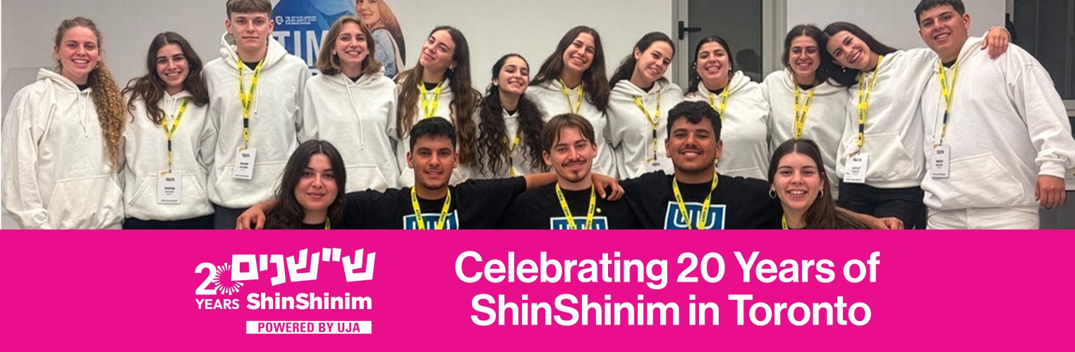 A group of young adults wearing white hoodies and yellow lanyards poses together, smiling. Text at the bottom reads, "Celebrating 20 Years of ShinShinim in Toronto."