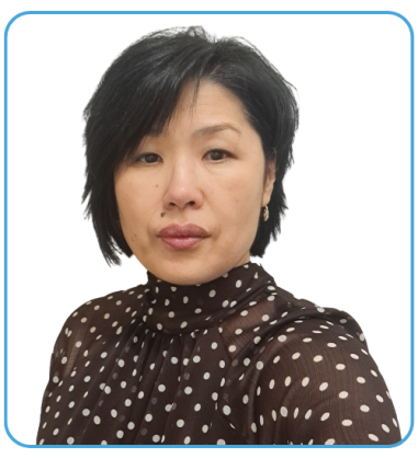 A woman with short black hair wearing a brown polka dot blouse is facing the camera against a solid black background.