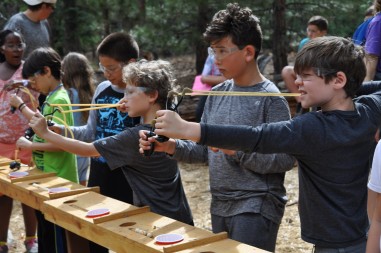 Kids shooting bows and arrows at summer camp