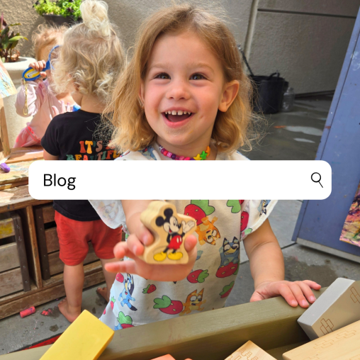 A preschool child shows off a Mickey block in an outdoor classroom environment