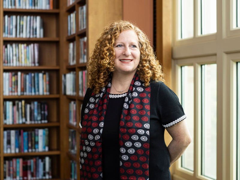 Chancellor Jennifer Mnookin standing by window and bookshelf